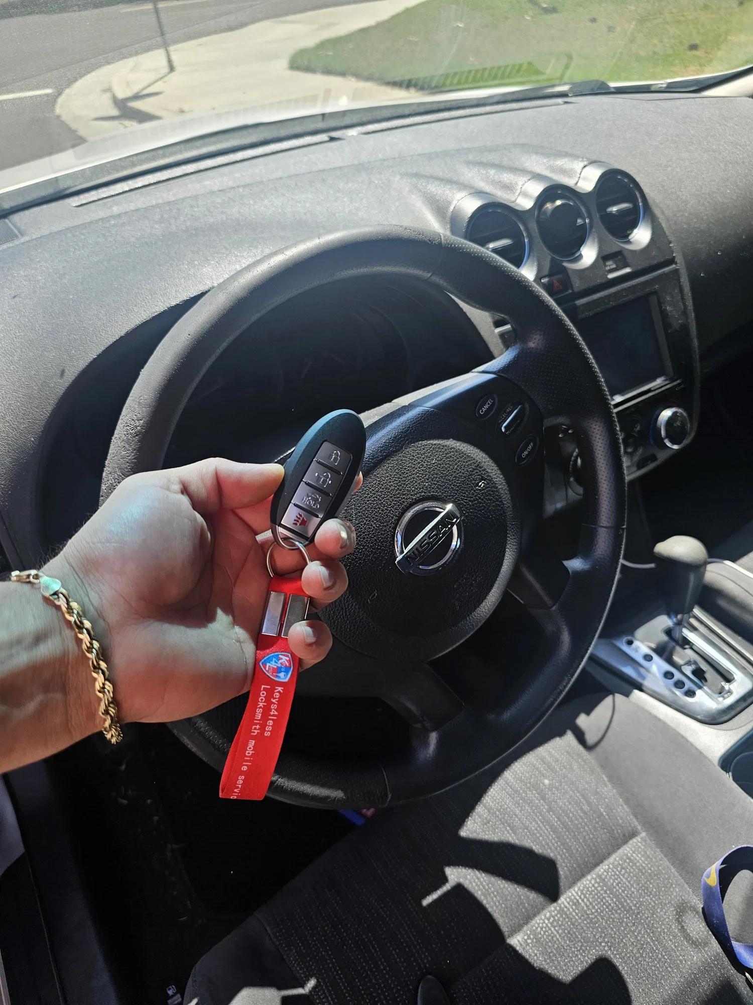 A Nissan key fob completed by Keys4Less, held inside the vehicle